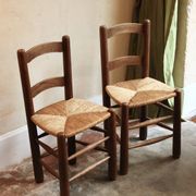 Pair of wooden chairs with woven straw seats.
