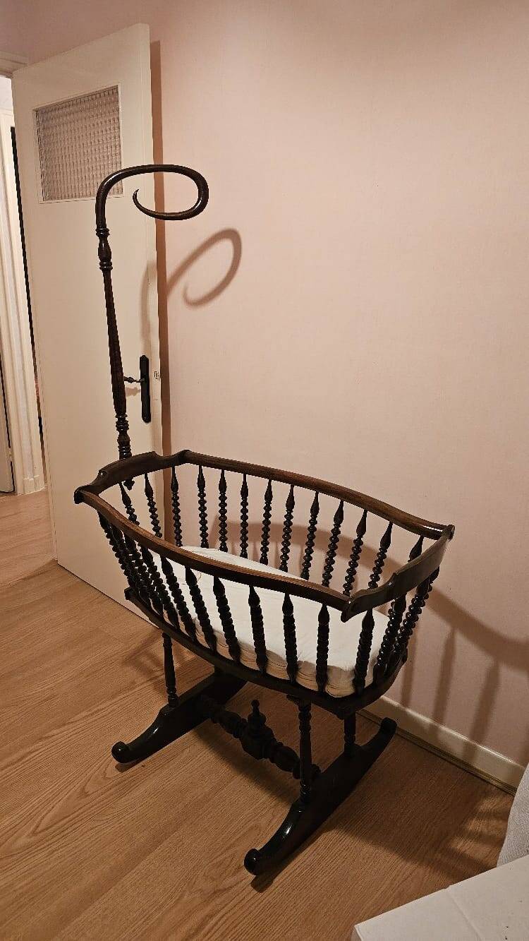 Old wooden rocking chair with turned legs and plumetis fabric.