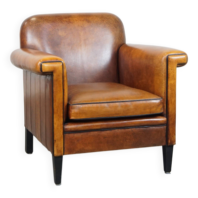Fauteuil Art Déco en peau de mouton avec finition élégante et passepoil noir.
