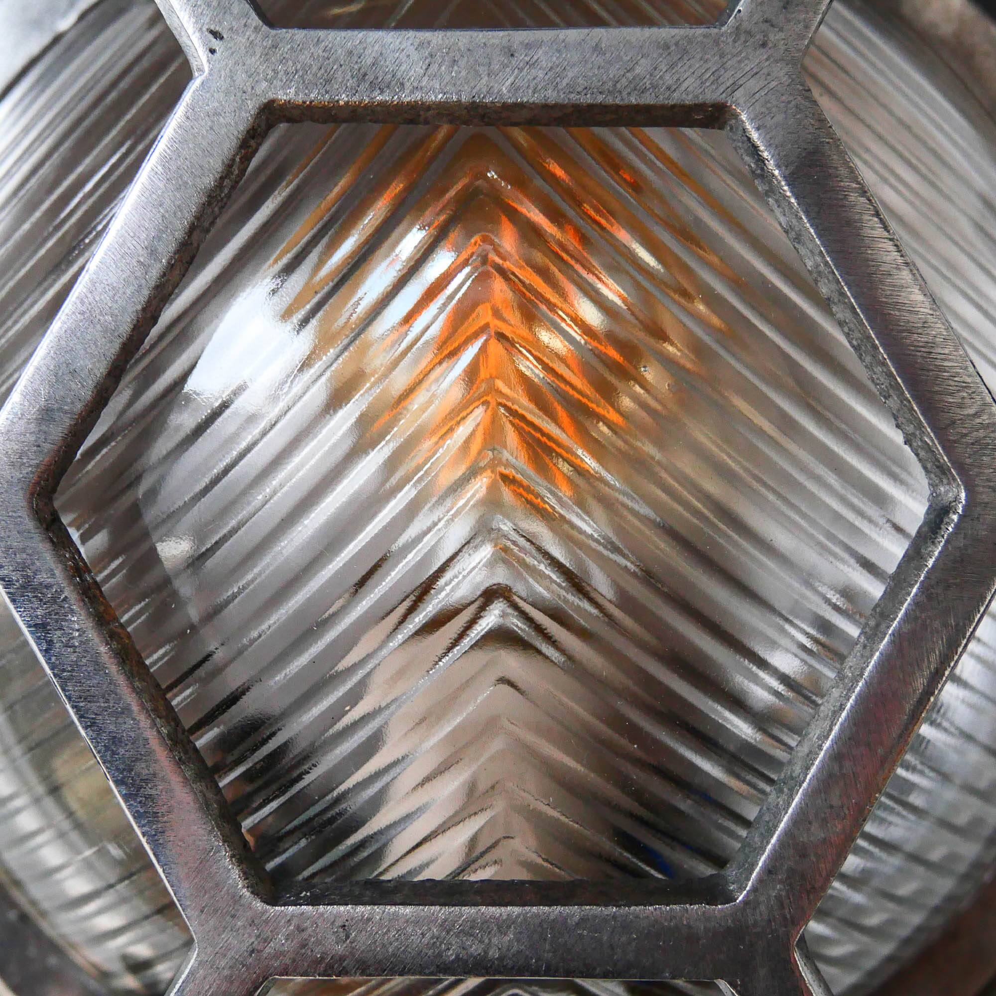 Old cast aluminum wall light with hexagonal grid and wide streaked glass.