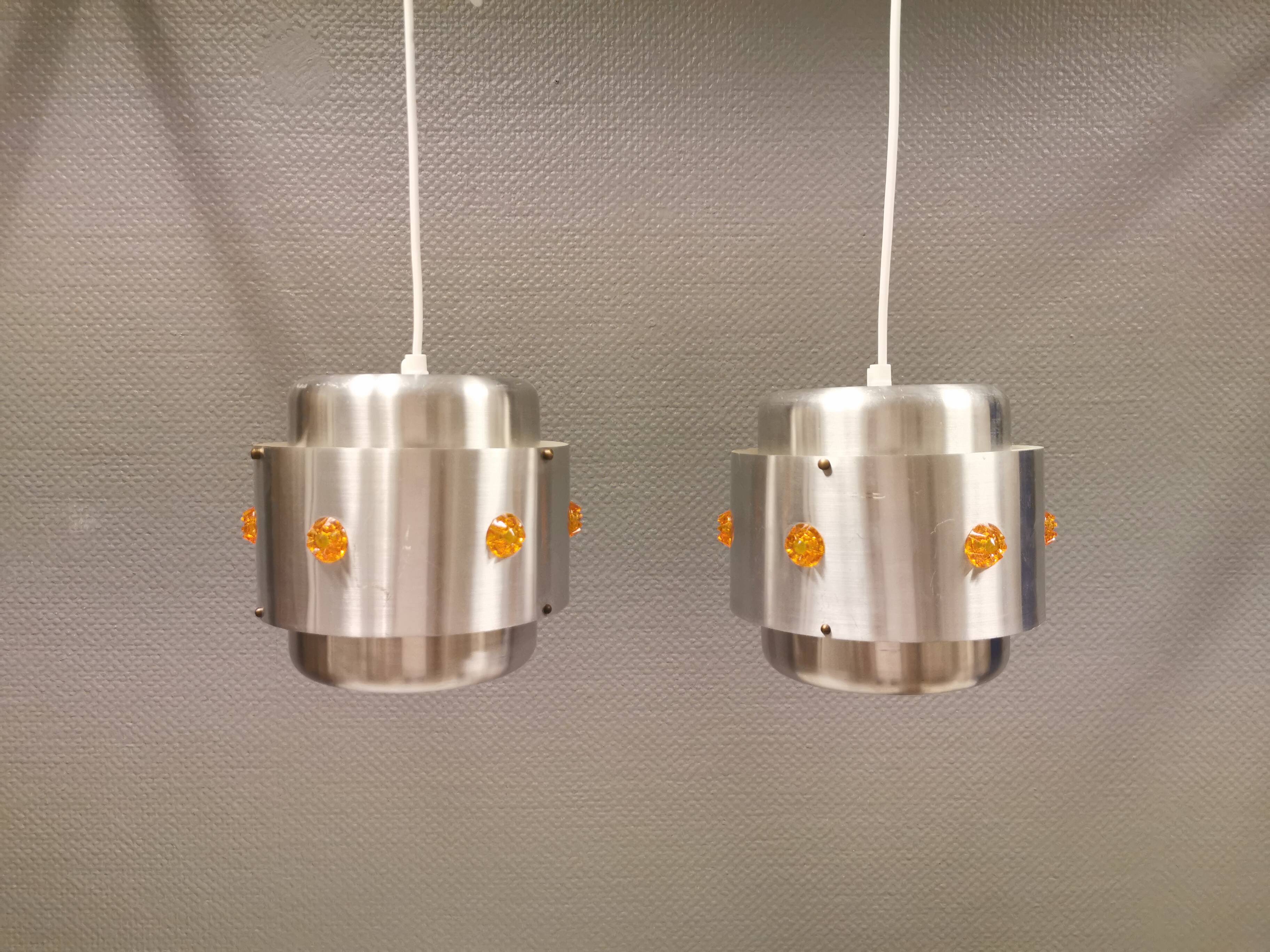 Two Space-Age hanging lamps, in silver-coloured aluminium with orange prisms.
