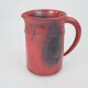 Red glazed ceramic jug with relief