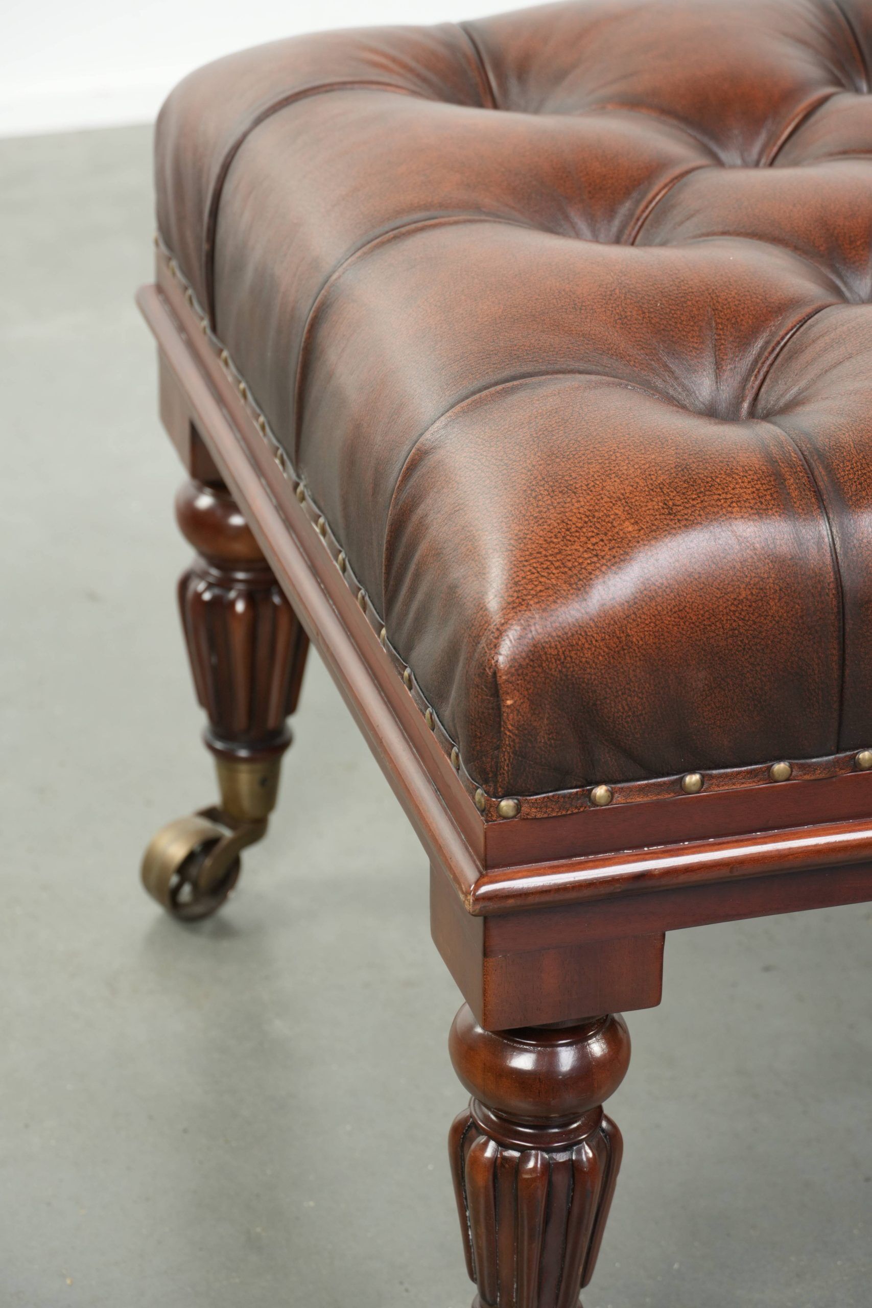 Brown cowhide Chesterfield ottoman in English style with ornate legs