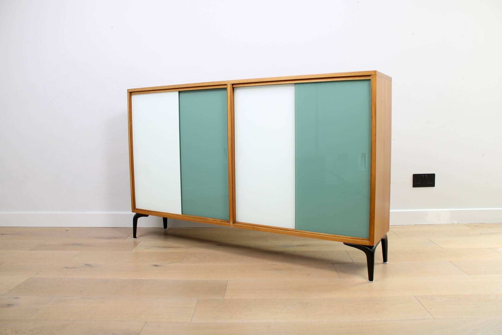 A vintage mid-century bookshelf/sideboard with green and white sliding door