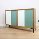 A vintage mid-century bookshelf/sideboard with green and white sliding door