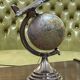 1960s terrestrial globe on a chrome stand with a plane flying over it.