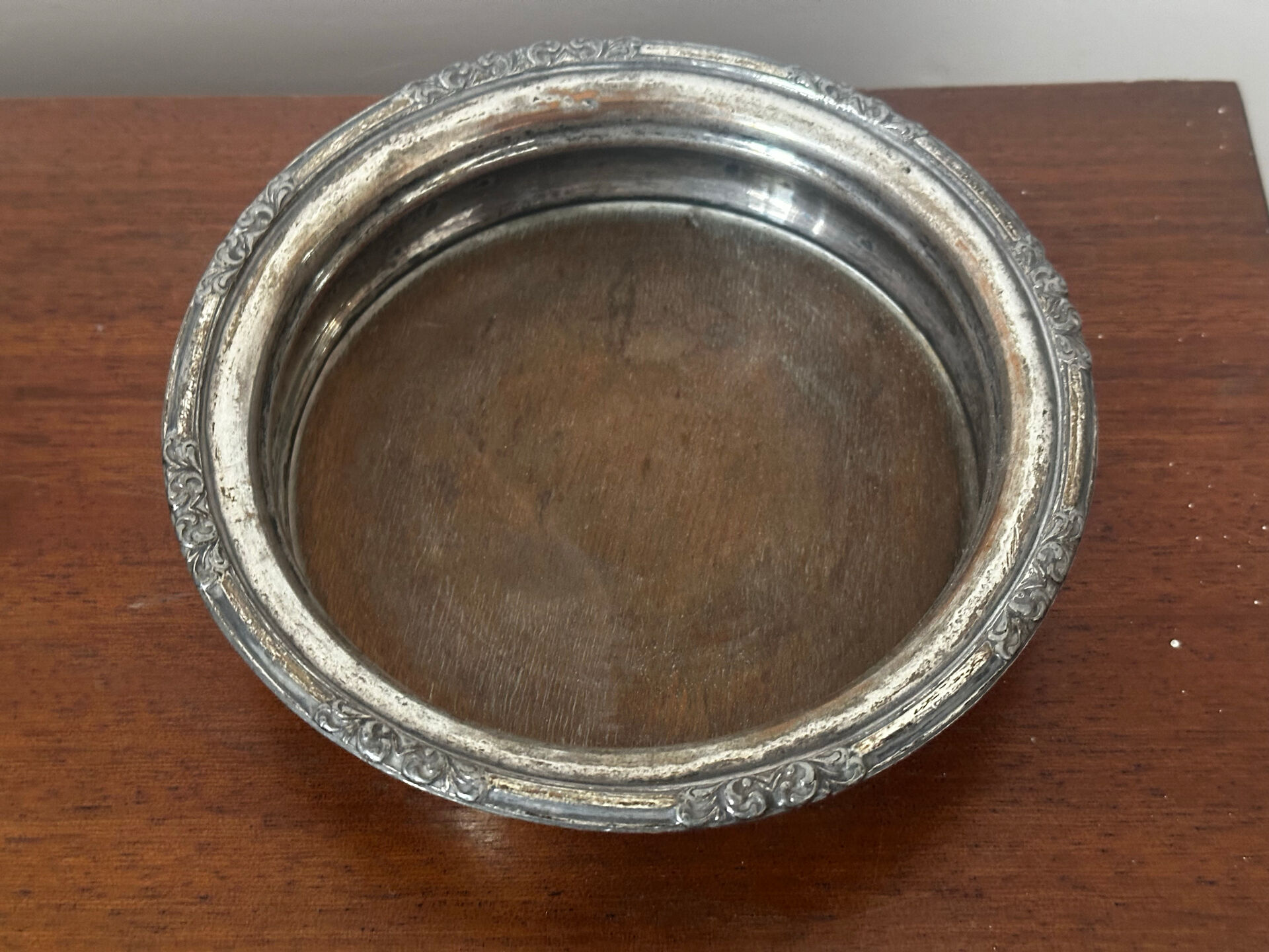 Antique silver-plated bottle coaster with floral decoration.