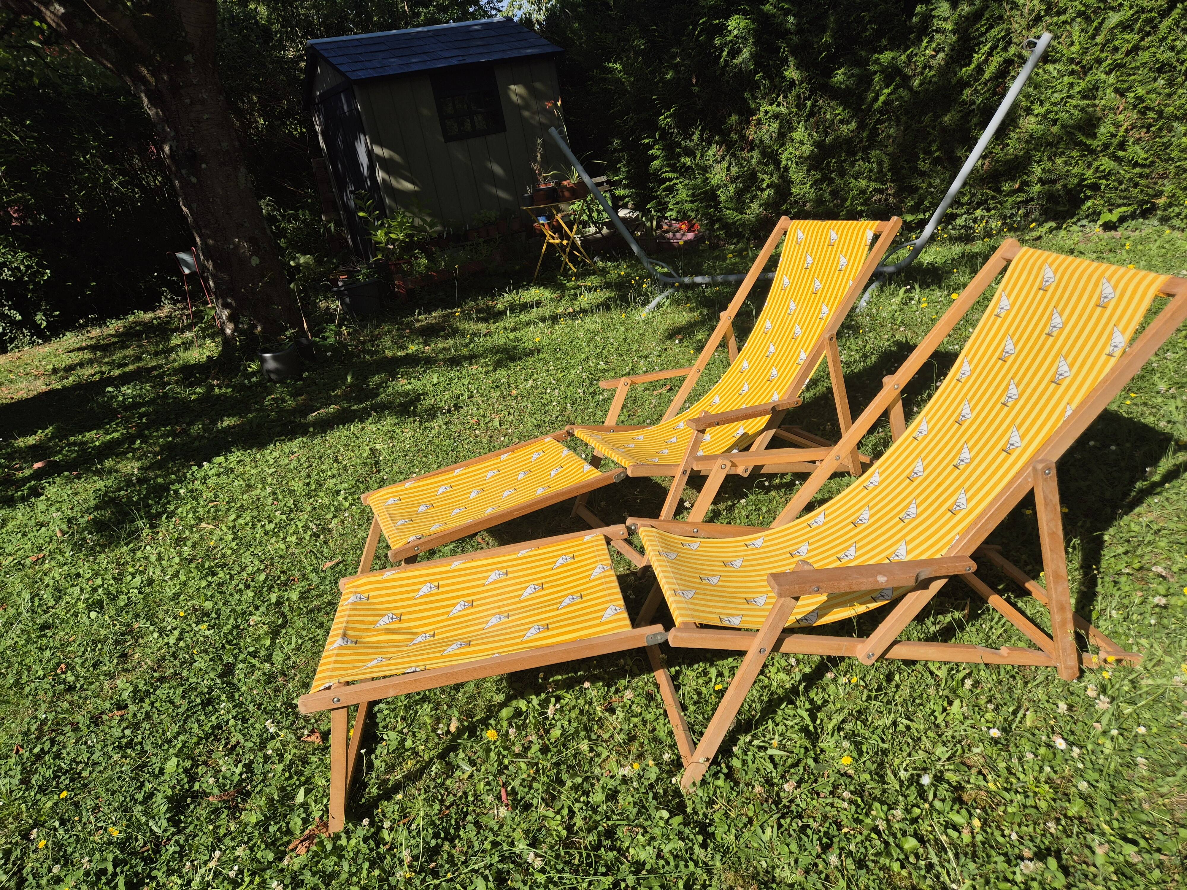 2 vintage Chilean deck chairs made of wood and yellow fabric printed with sailboats, with footrests.