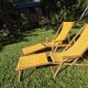 2 vintage Chilean deck chairs made of wood and yellow fabric printed with sailboats, with footrests.
