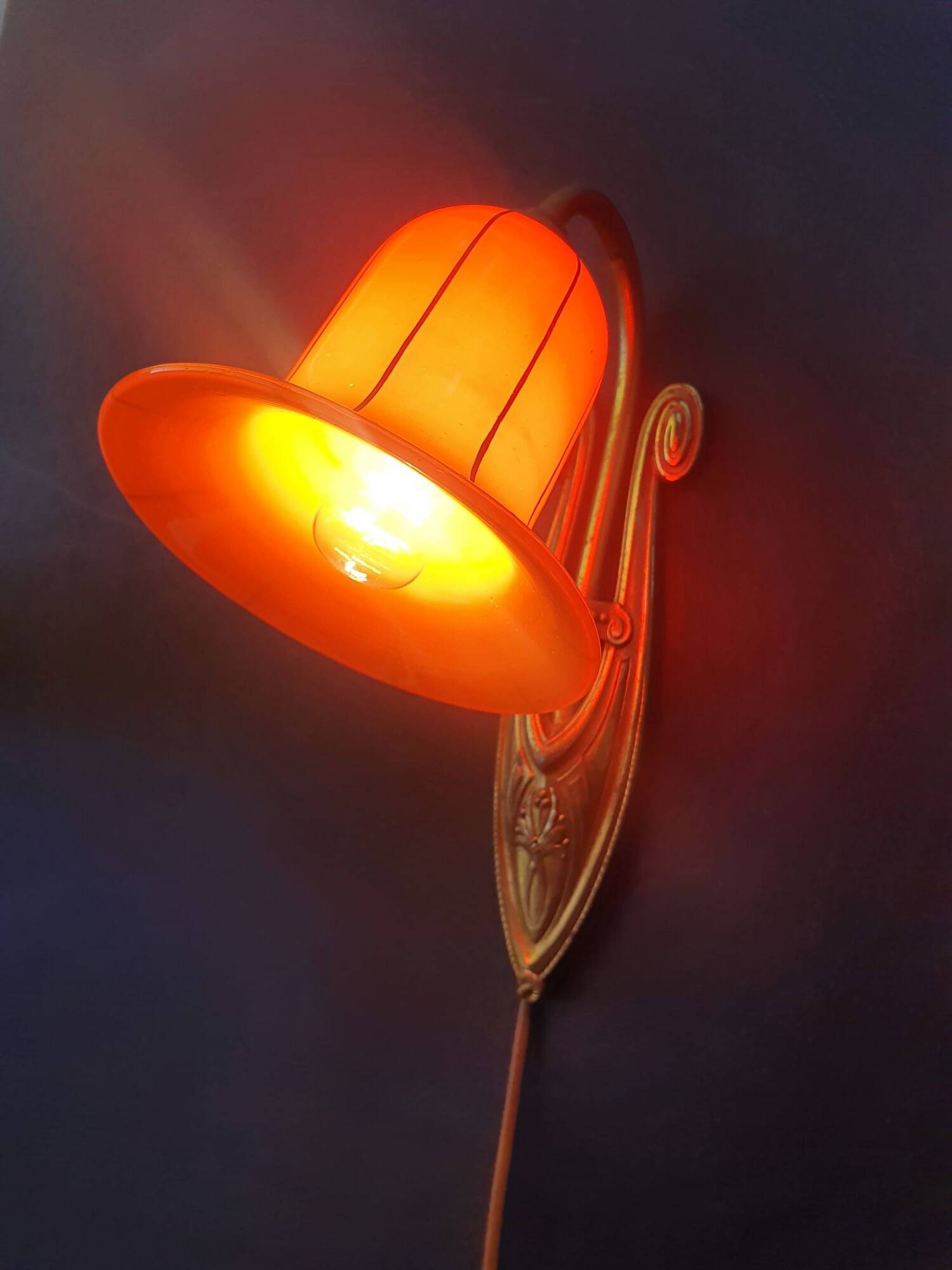 Art Deco wall light in brass with an orange globe.