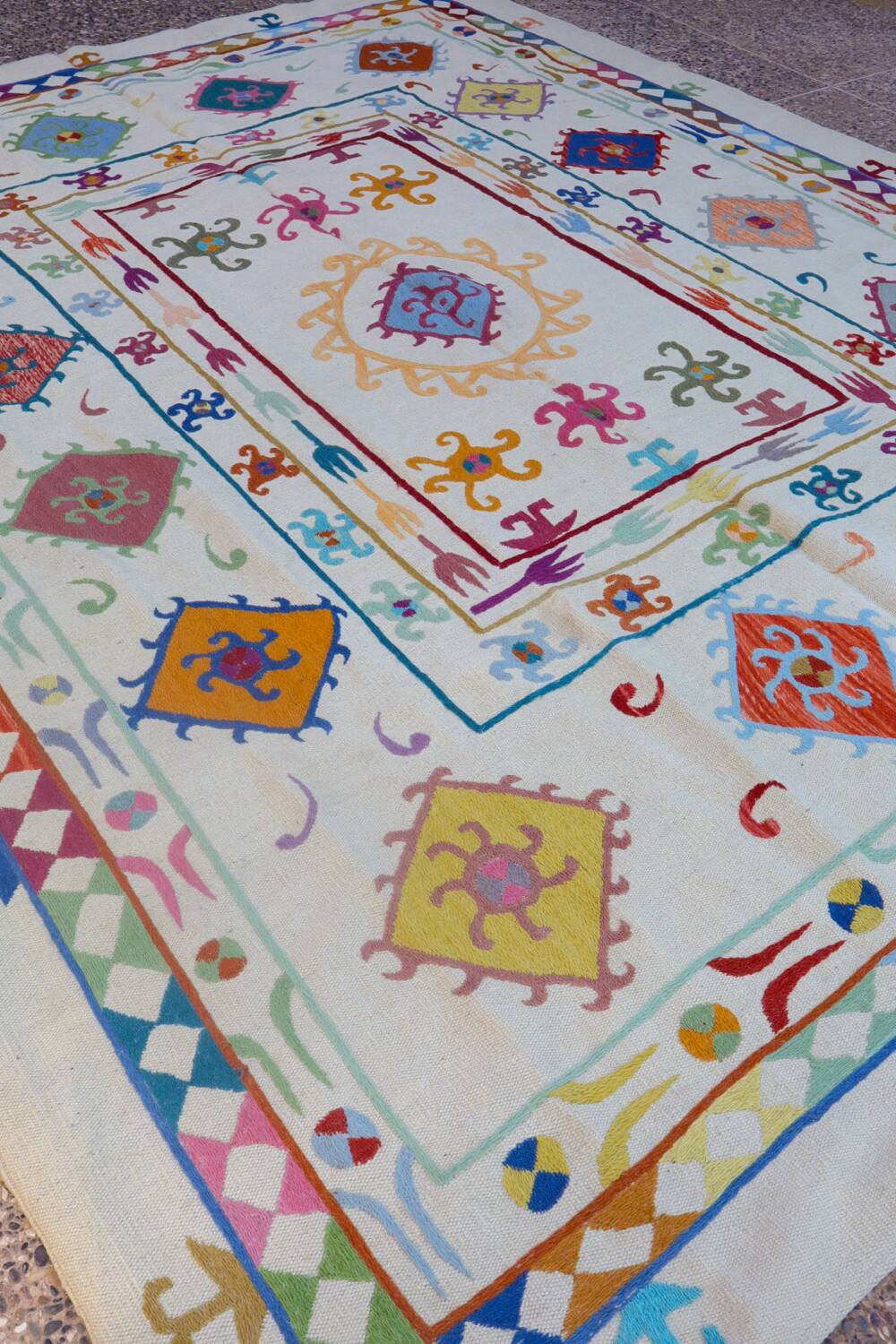 White suzani kilim rug with multi-colored embroidered patterns