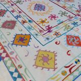 White suzani kilim rug with multi-colored embroidered patterns