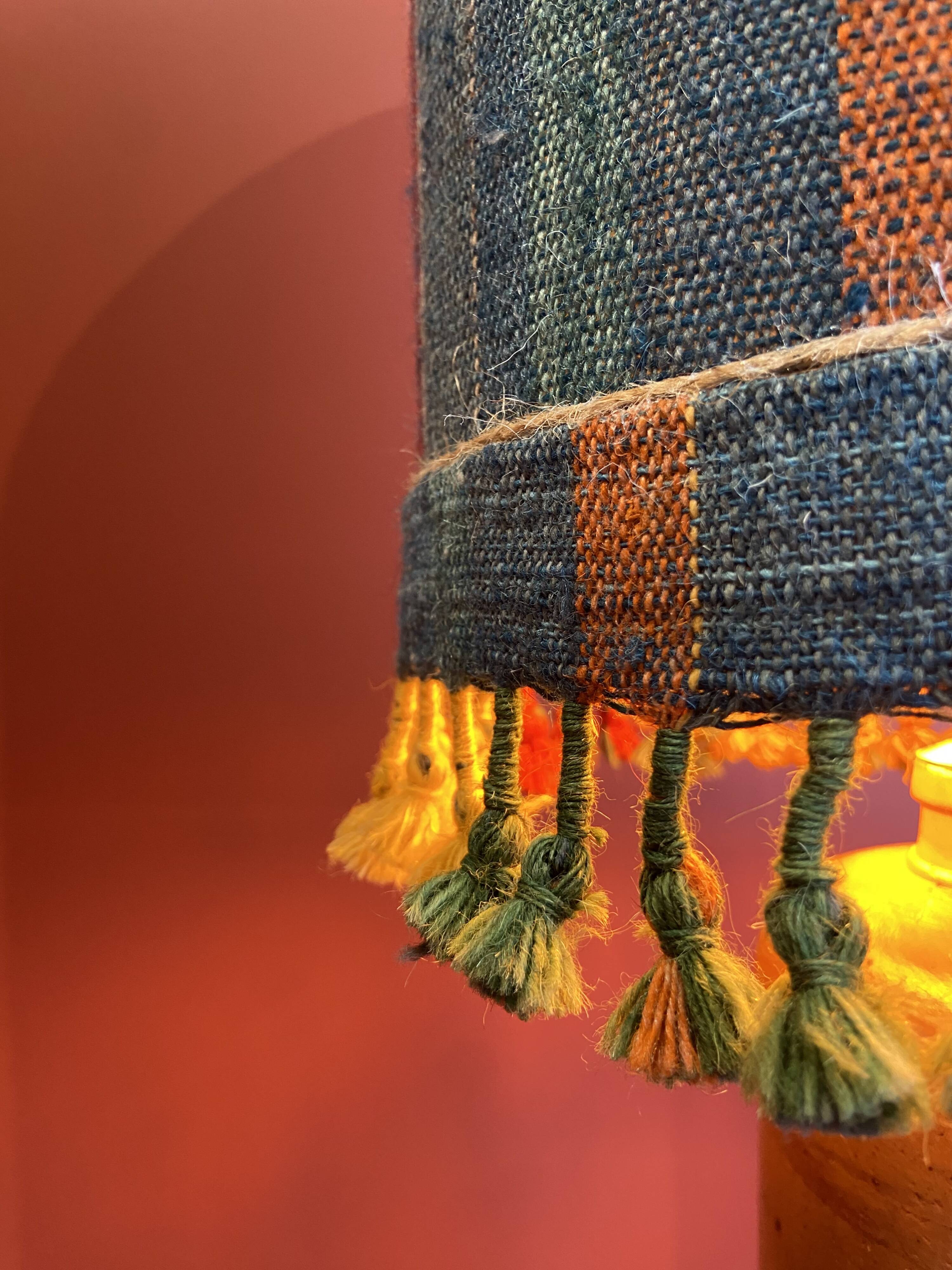 "Stoneware Bottle Lamp" with a multicoloured blue lampshade handwoven in India.