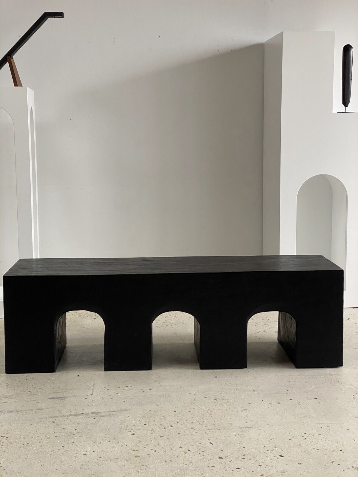 Black solid monoxyl wood bench carved into 3 arches