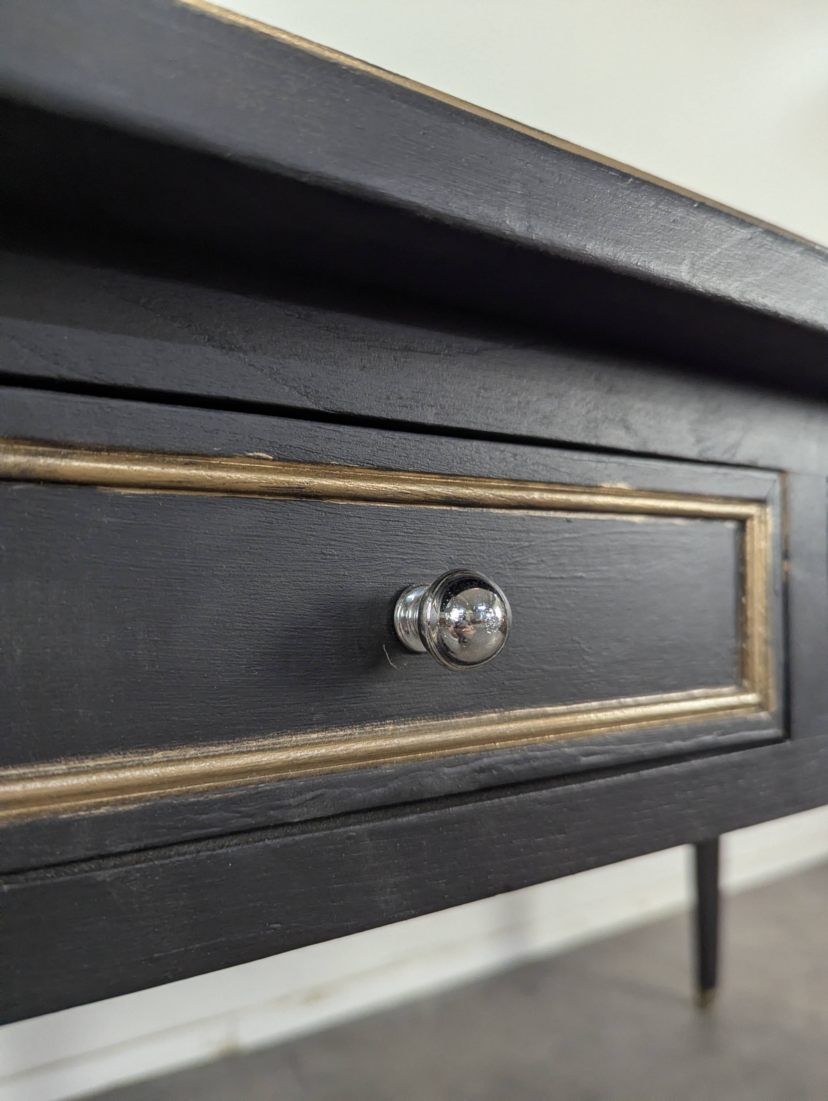 Large flat desk in Louis XVI style, black lacquered with gold highlights.