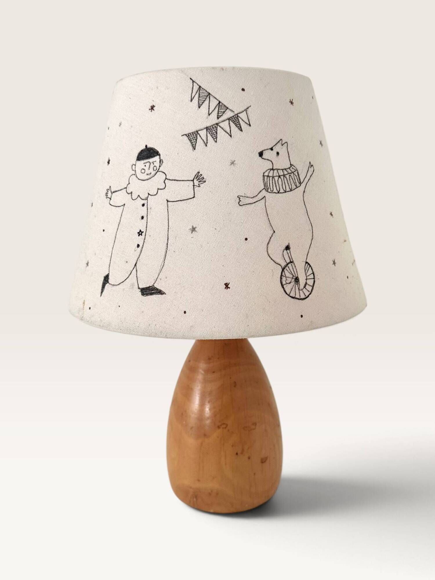 Wood-turned lamp with a hand-drawn lampshade, circus patterns.