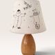 Wood-turned lamp with a hand-drawn lampshade, circus patterns.