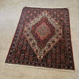 Ancient Persian carpet, wool, red tones, hand-knotted.