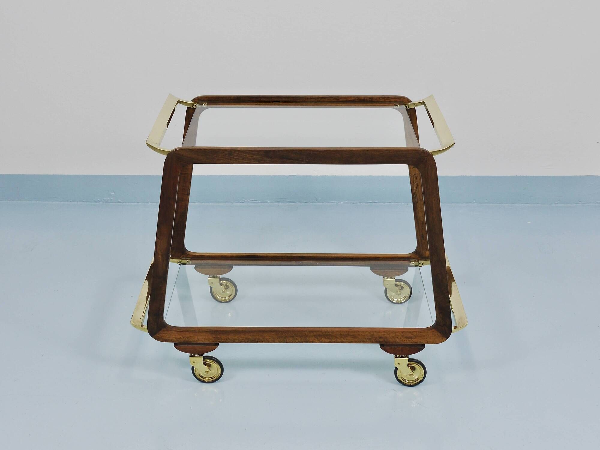 May include: A mid-century modern bar cart with a dark wood frame and two c