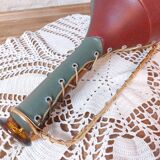 Amber bottle covered in colored leather with handle surrounded by wire, vintage