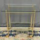 Service trolley on wheels with two glass shelves and a brass frame.