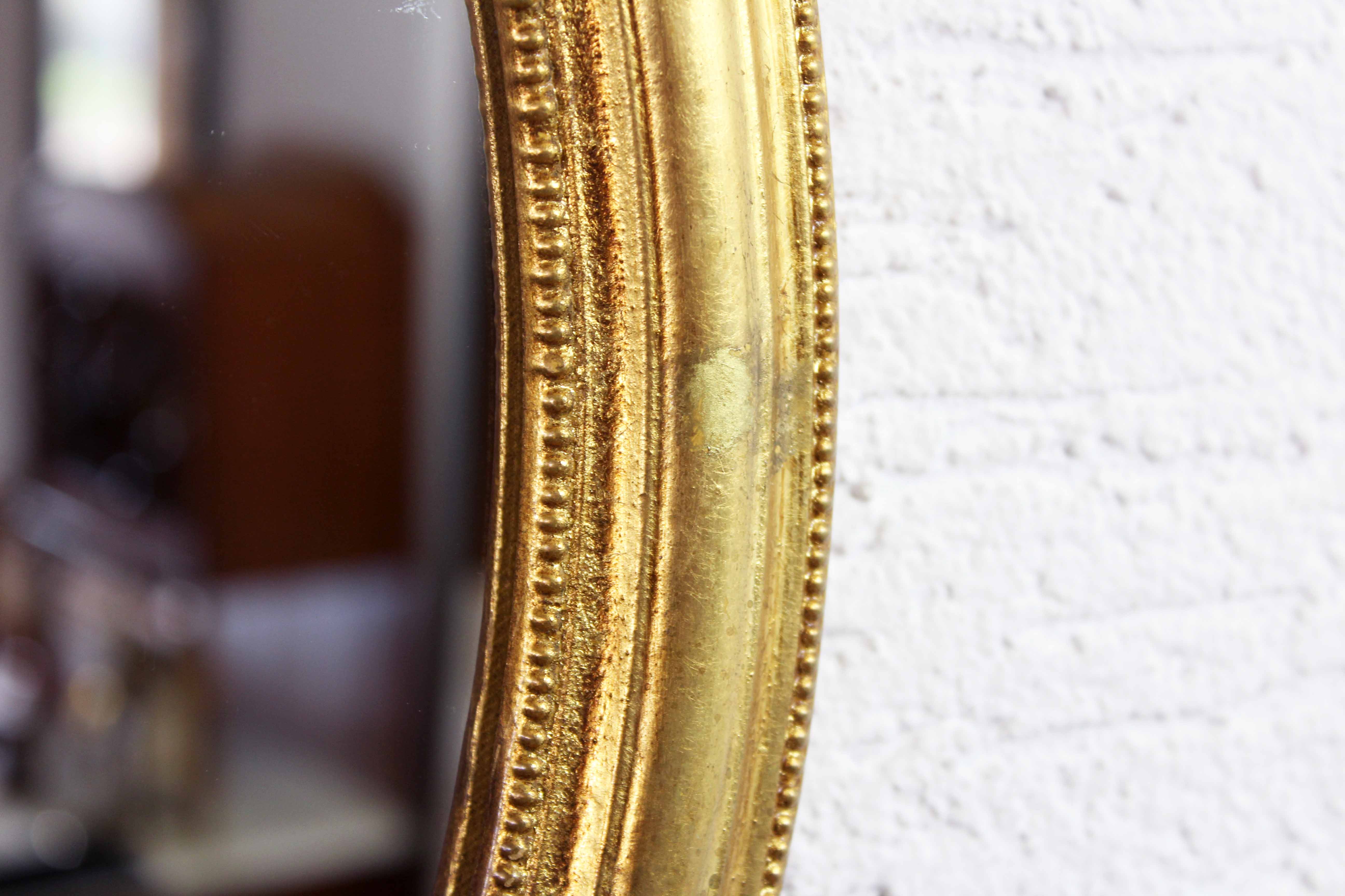 Golden oval mirror with leaf