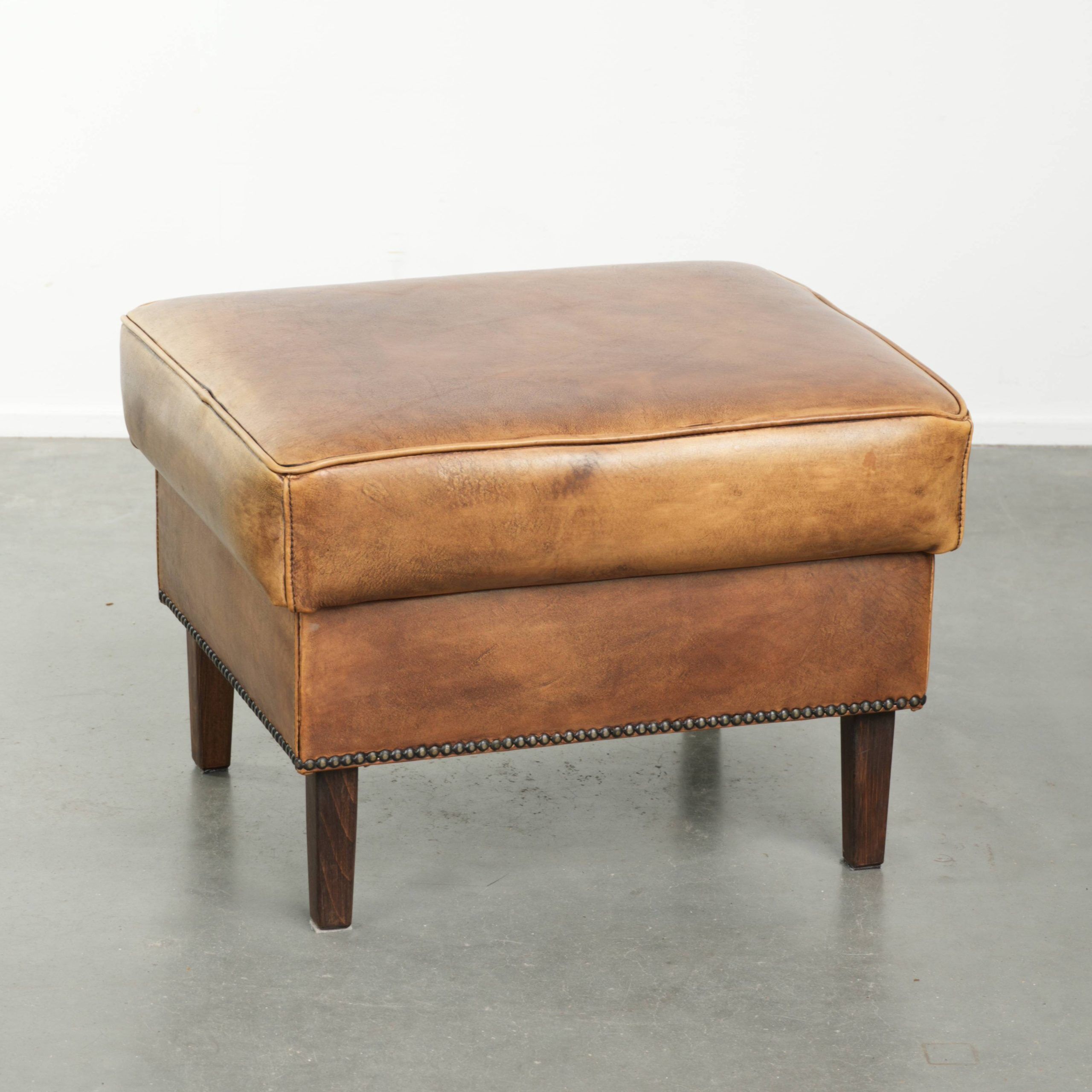 Cowhide ottoman with a beautiful patina finished with decorative nails