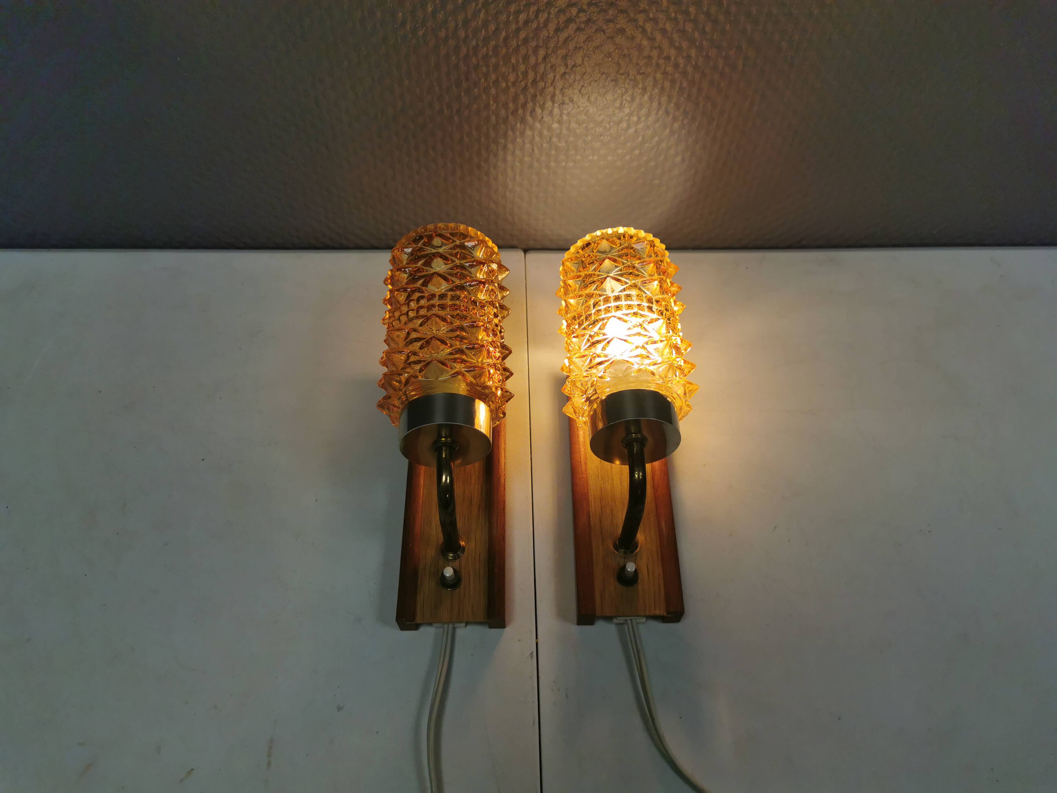 A set of wall lamps in teak wood, with amber colored glass
