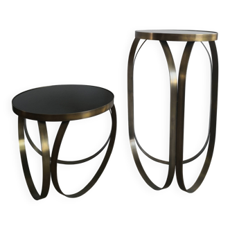 2 round tables with golden metal legs and black glass tops.