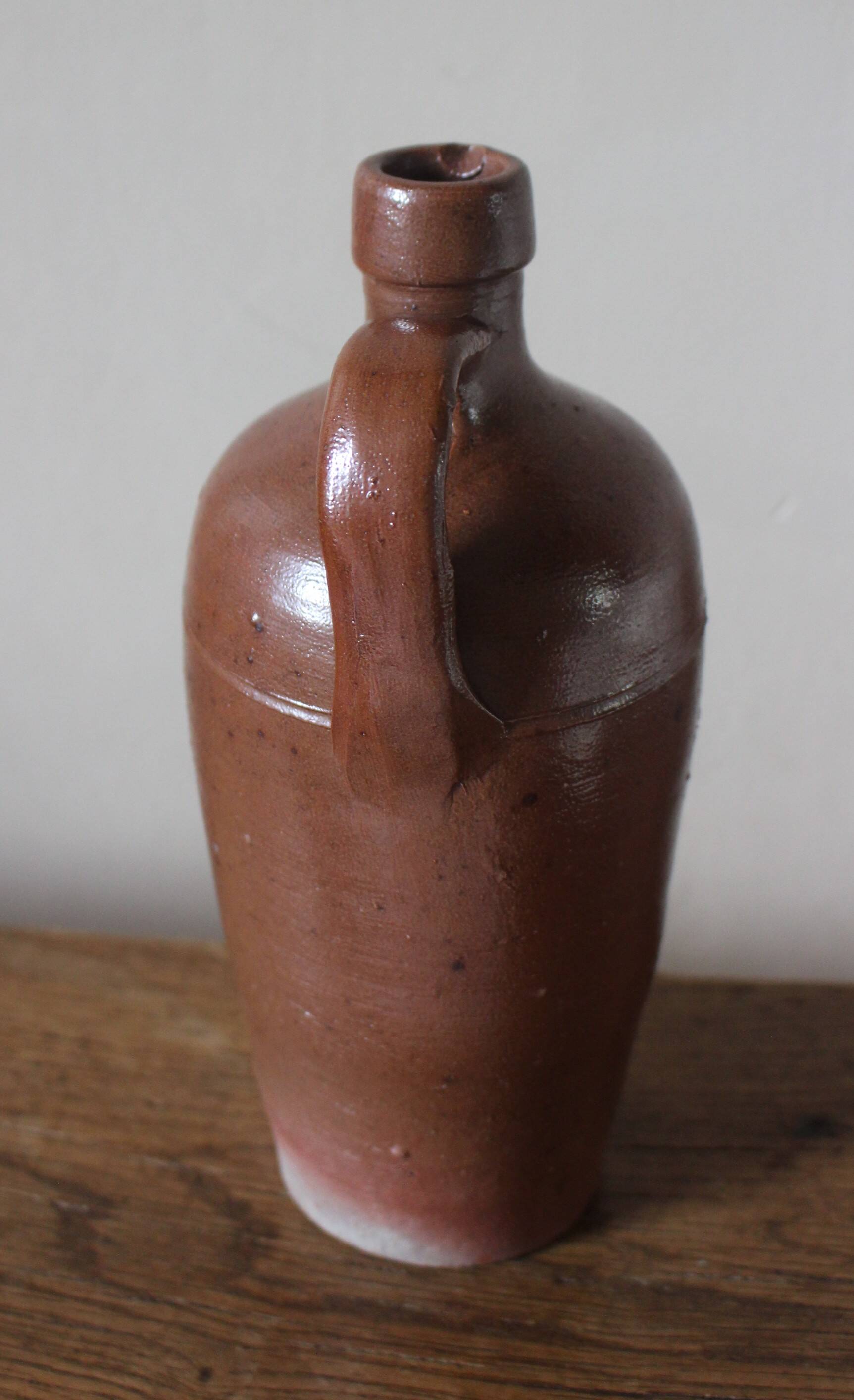 Vintage stoneware liqueur bottle with handle and spout.