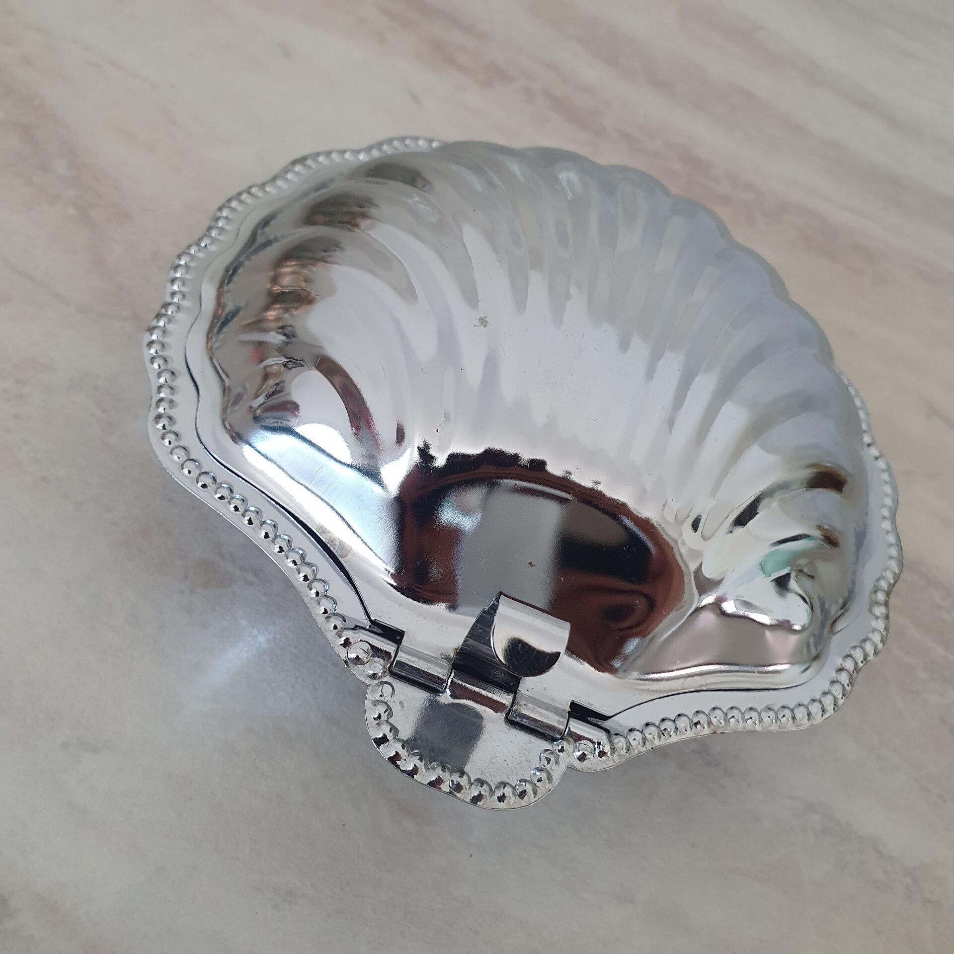 Scallop shell butter dish in stainless steel with its white glass saucer.