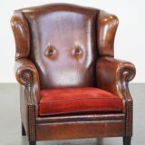 Sheep leather wingback chair with a red corduroy seat cushion and patina