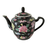 Vintage Chinese teapot with floral polychrome decoration on a black background.