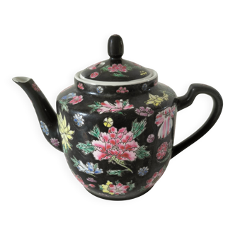 Vintage Chinese teapot with floral polychrome decoration on a black background.