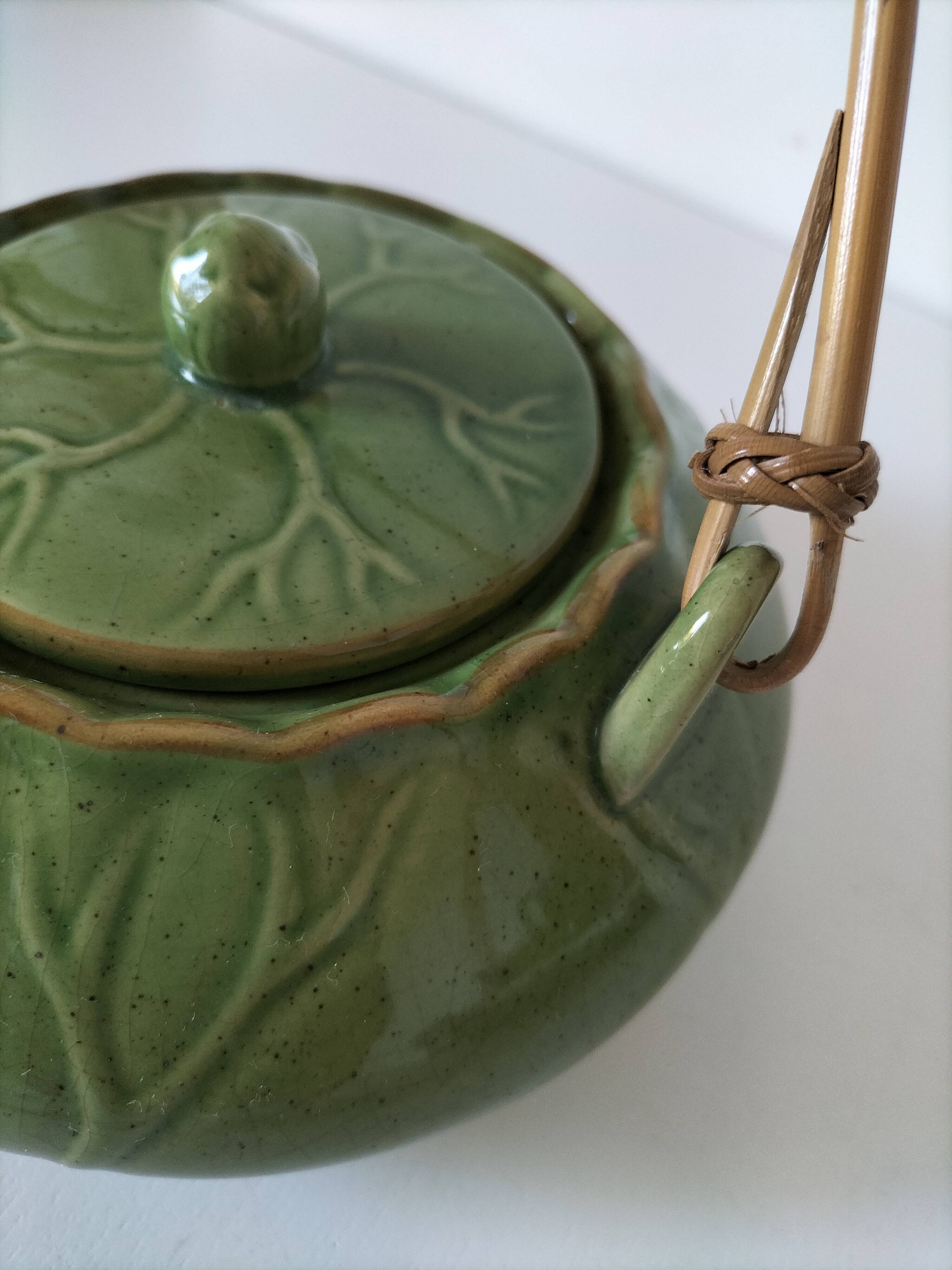 Vintage green teapot with lotus decoration and bamboo handle.