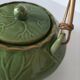 Vintage green teapot with lotus decoration and bamboo handle.