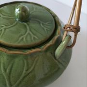 Vintage green teapot with lotus decoration and bamboo handle.