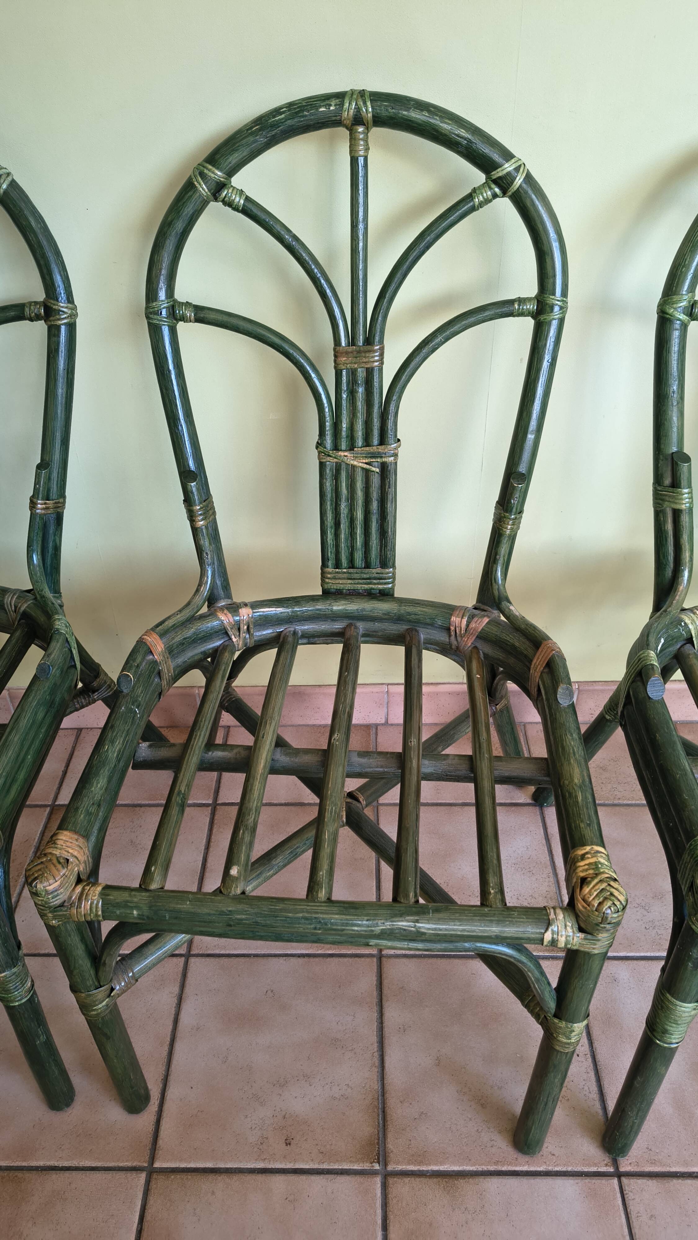 Round rattan table with glass top and 4 green rattan chairs.