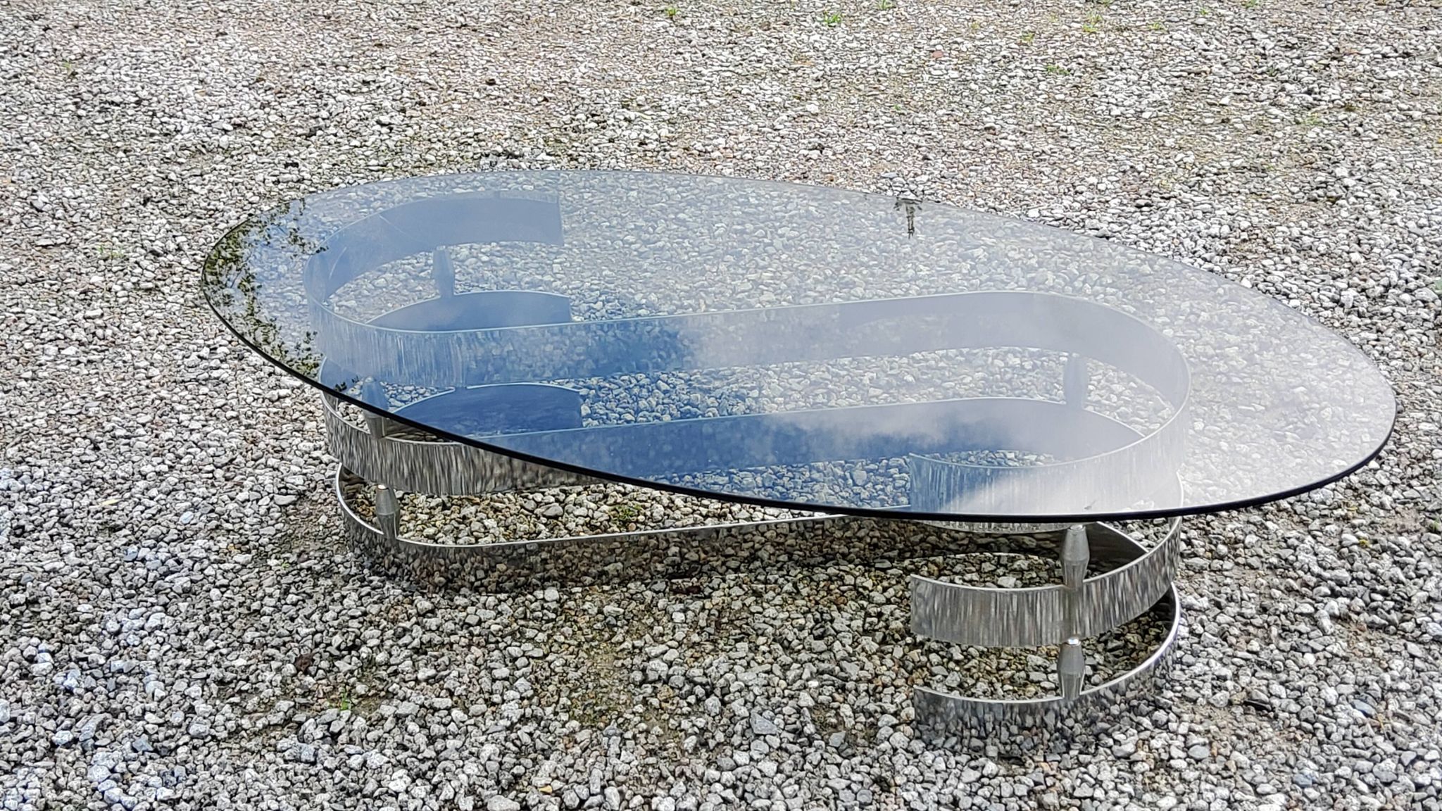 Oval coffee table of the 70s chromed metal base in s smoked glass top