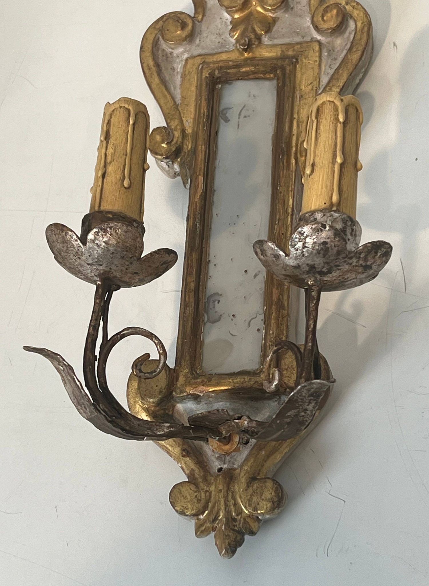 Pair of wall sconces in carved wood and silvered and gilded patinated metal with a central mirror.