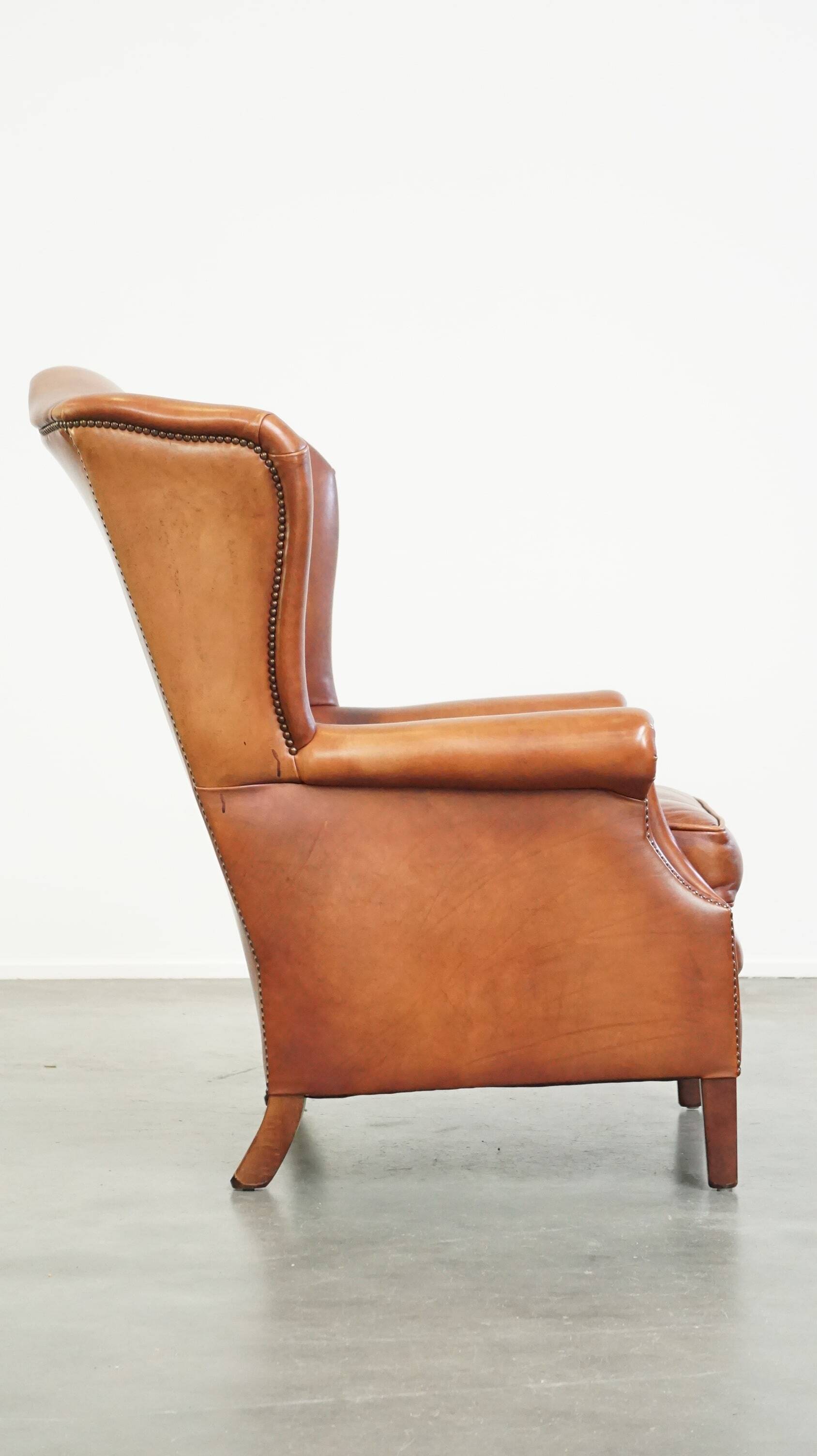 Fauteuil en cuir confortable et bien entretenu, fini avec des clous décoratifs de style anglais