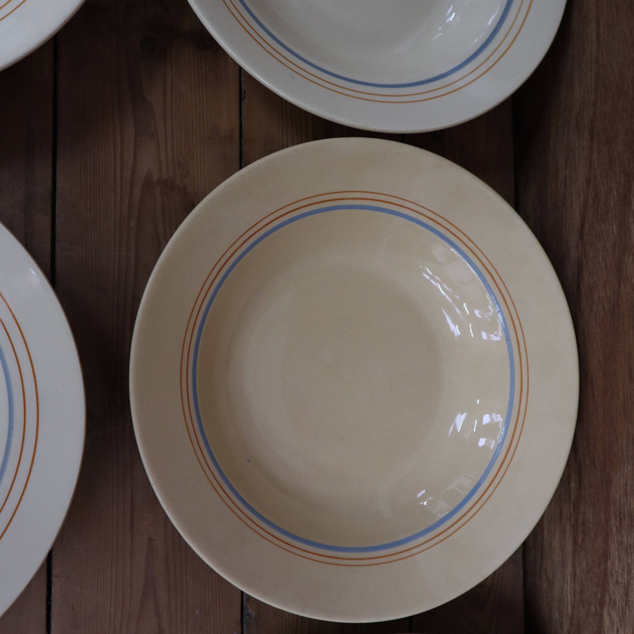 6 old cream-coloured deep plates with blue/orange trim.