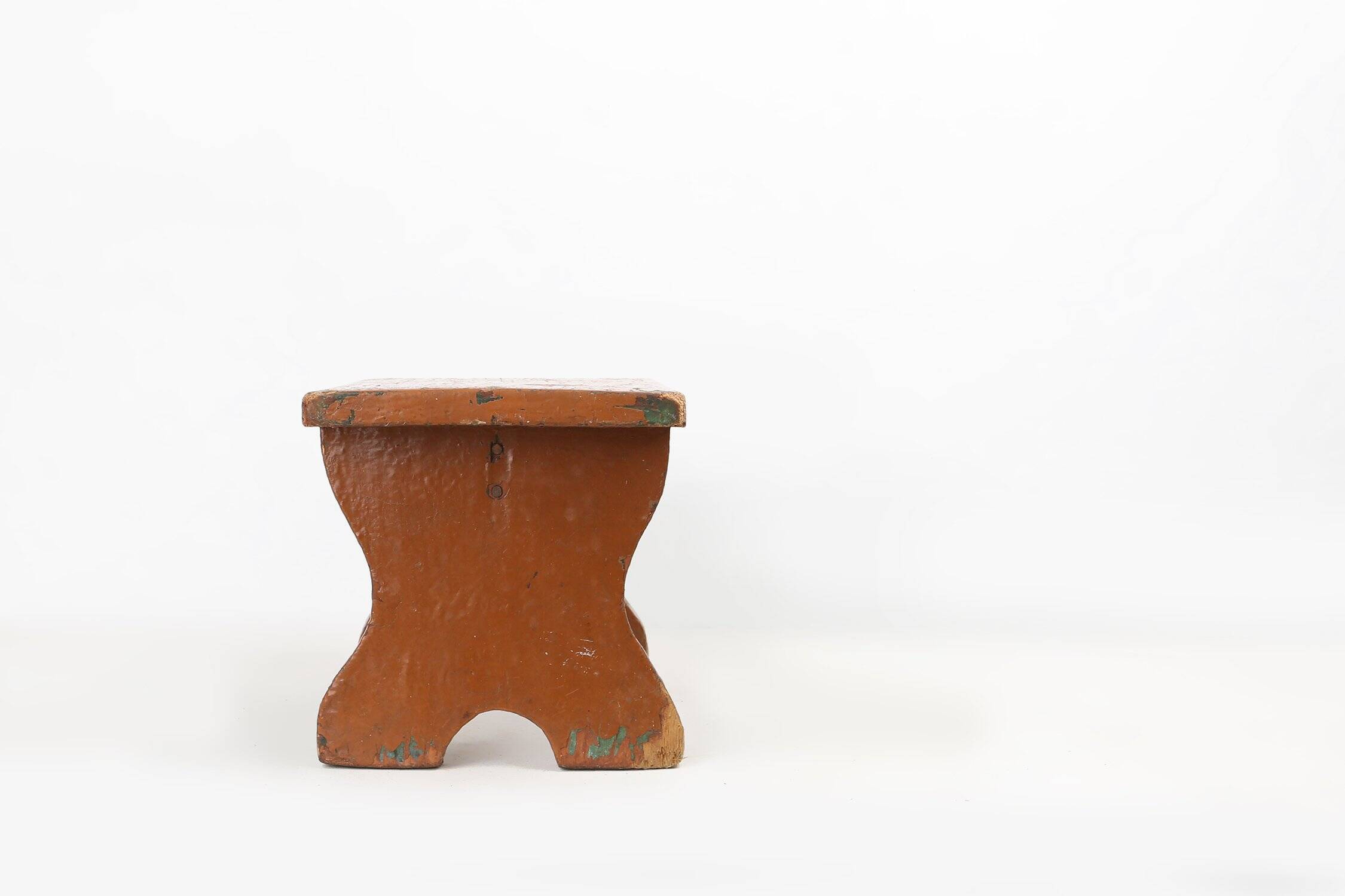 Tabouret bas rustique français en bois peint en terre cuite, années 1890.