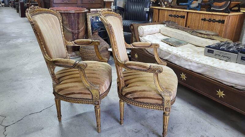 A pair of gilded wooden armchairs in the Louis XVI style.