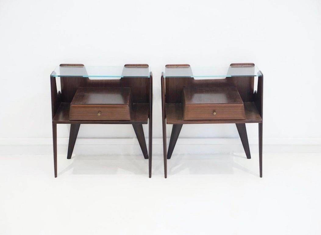 Pair of modernist Italian bedside tables in wood with a glass top.