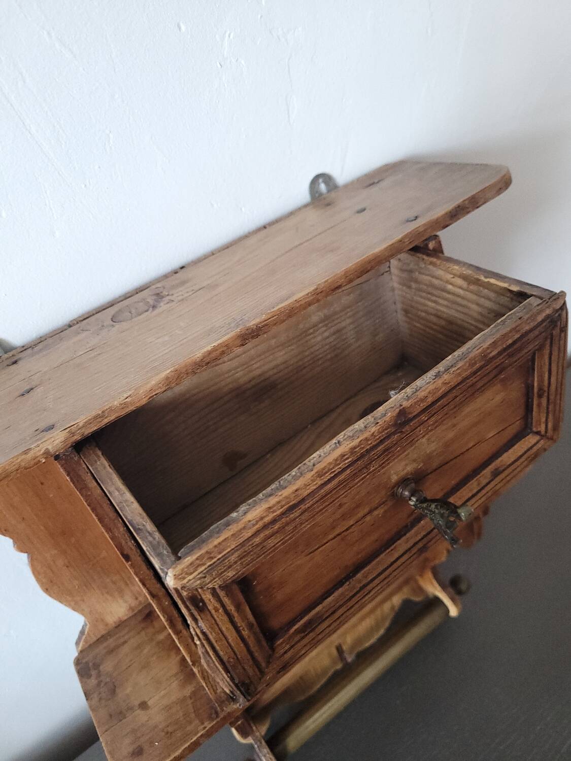 Small antique wall shelf with a drawer in light solid wood.