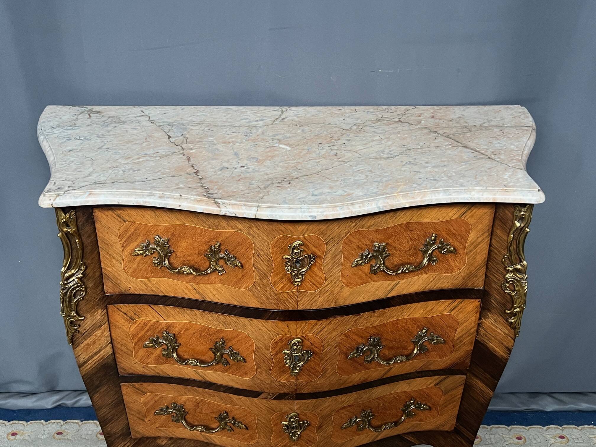 Louis XV style commode with rosewood veneer, gilded bronze mounts, and marble top.