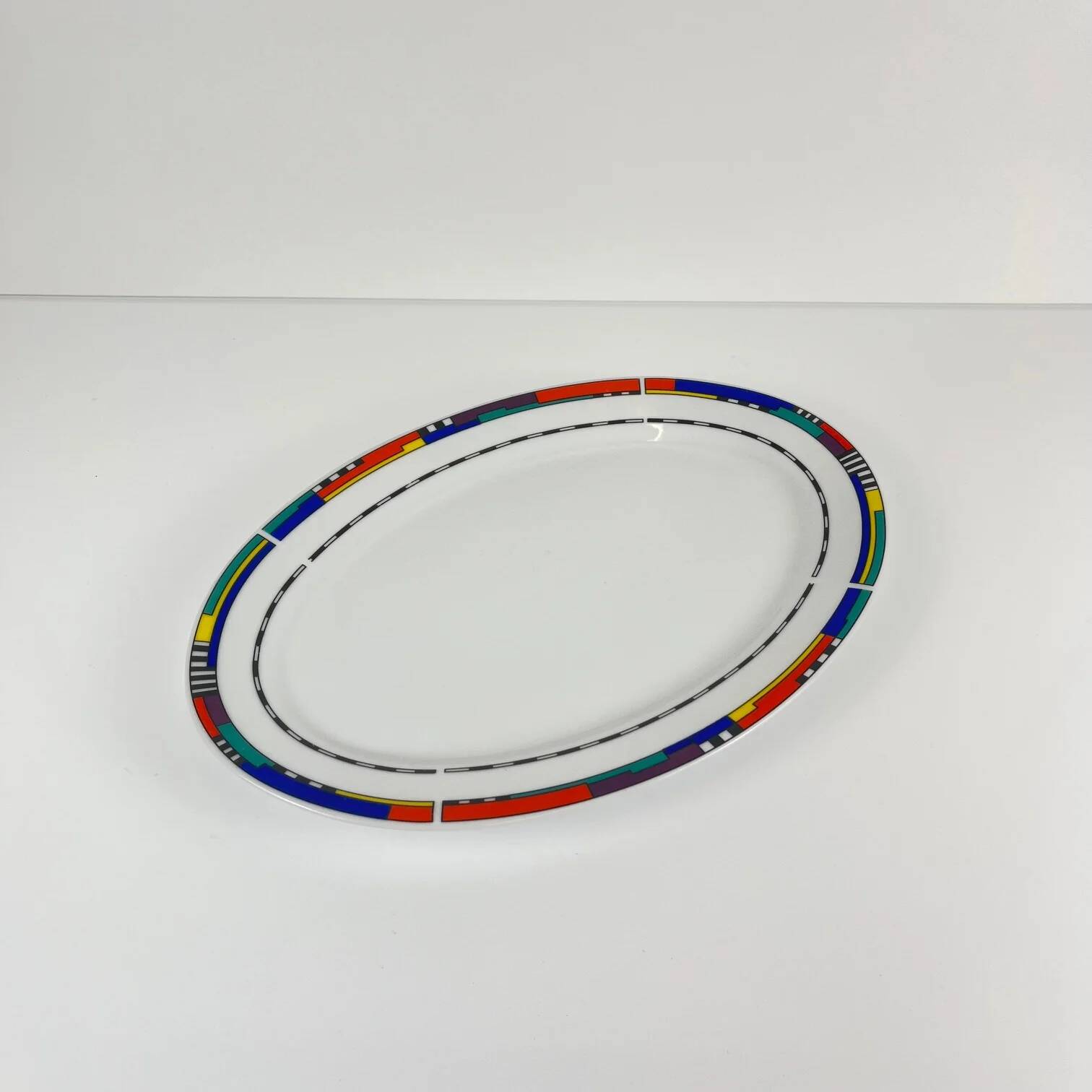 Oval porcelain plate by Van Well, multicoloured geometric border, 1980.
