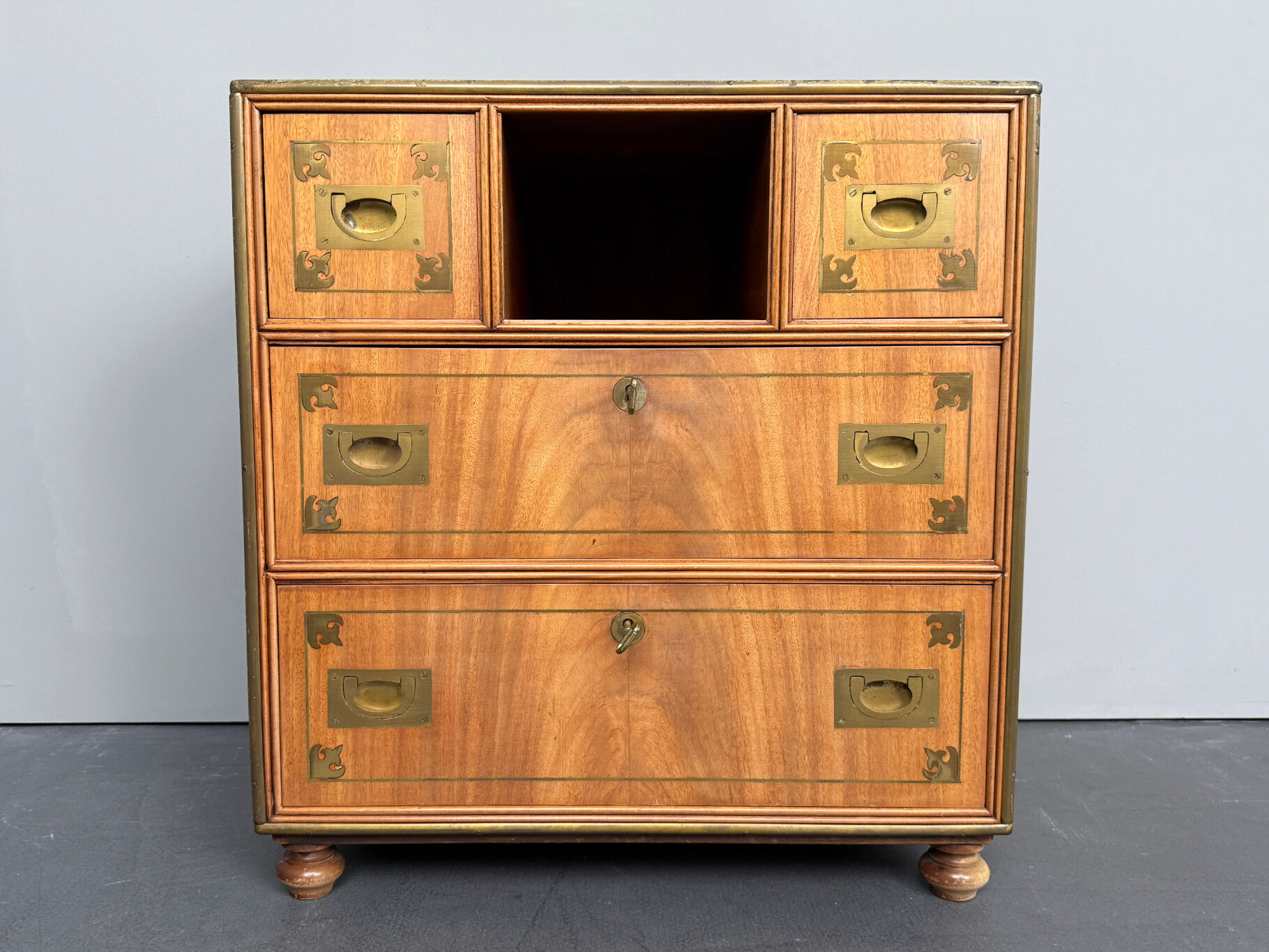 Antique campaign chest / ship’s chest, England, 1940s. Mahogany with a distinctive grain, brass inlays and hardware.