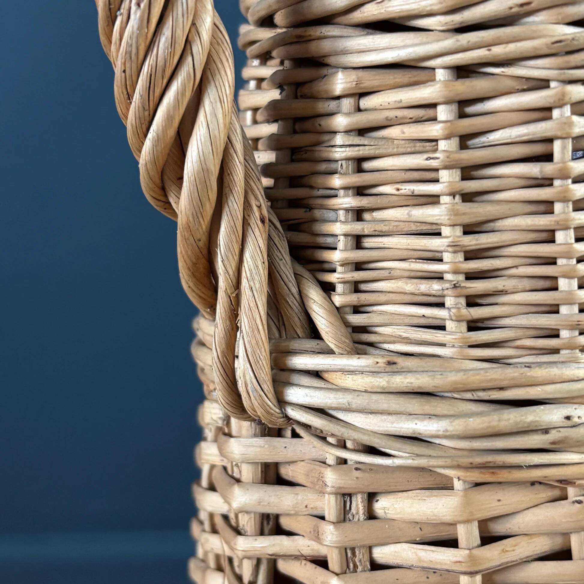 Bouteille en verre ambré dans son panier à poignée en osier